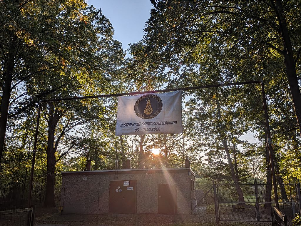Banner „Westerncamp Schwarzpulverunion 05. – 11.10.2026“ am Eingang des Vereinsgeländes im Gegenlicht